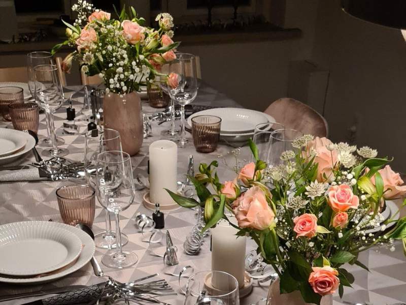 Pyntet nytårsbord med ferskenfarvede blomster