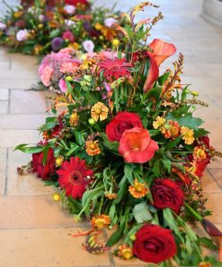 Båredekoration i brændte farver på kirkegulvet med andet begravelsesbinderi