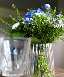 Blå og hvid buket med blå studenterhue set nedefra i en glasvase