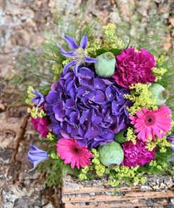 Buket i lilla og pink farver ligger på barkstykker