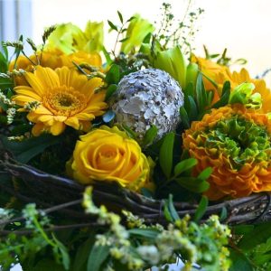 Nærbillede af et pynte påskeæg gule gerbera, roser og chrysanthemum