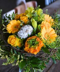 Nærbillede af en orange og gul buket i påsketema med små grene og påskeæg