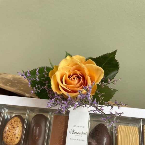 Nærbillede af en chokoladeæske og en orange rose