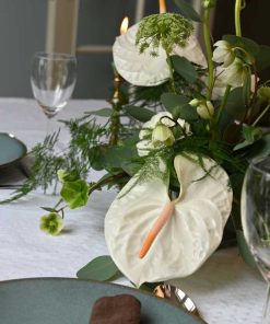 Hvid bordpynt med anthurium og andre blomster på bord