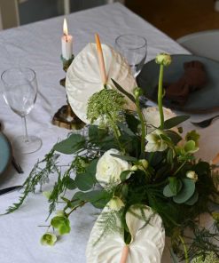 Hvid bordpynt med anthurium og andre blomster på bord