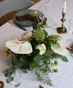 Hvid bordpynt med anthurium og andre blomster på bord