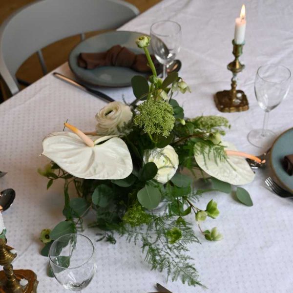 Hvid bordpynt med anthurium og andre blomster på bord