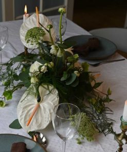 Hvid bordpynt med anthurium og andre blomster på bord