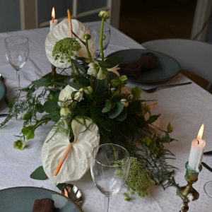 Hvid bordpynt med anthurium og andre blomster på bord