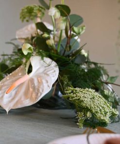 Hvid bordpynt med anthurium og andre blomster på bord