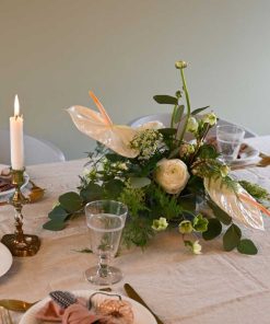 Hvid bordpynt med anthurium og andre blomster på bord