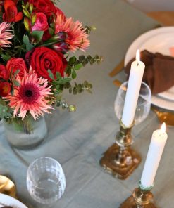 Hyggeligt bord med levende lys og en buket i røde og lyserøde farver