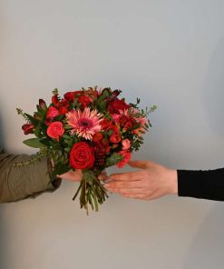 Buket i lyserøde og røde farver, der gives i mellem to personer