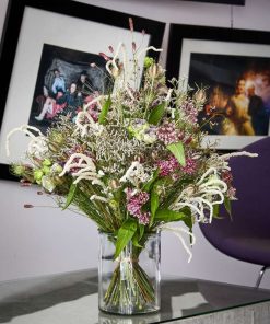 Luftig og livlig buket med sommerblomster stående på et sofabord