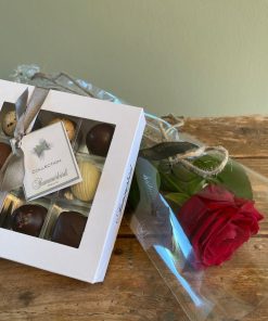Nærbillede af chokoladeæske med 9 stk. fra summerbird og en langstilket rød rose pakket i cellofan