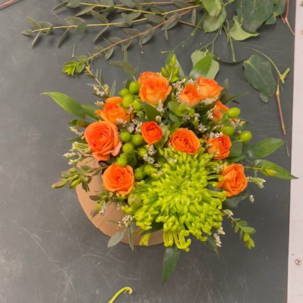 En blomsteræske set oppefra med orange blomster og stor grøn Chrysanthemum