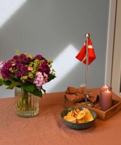 Buket i pink/lilla farver pyntet med små flag på bord med dug og flag