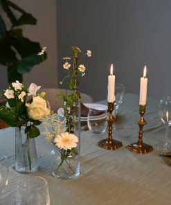 Små vaser med forskellige blomster i hvide farver på dækket middagsbord