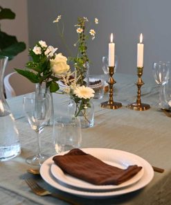 Små vaser med forskellige blomster i hvide farver på dækket middagsbord