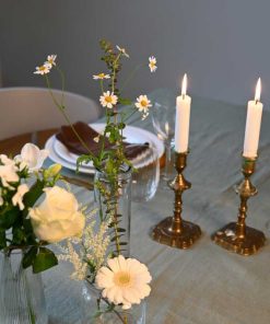 Små vaser med forskellige blomster i hvide farver på dækket middagsbord