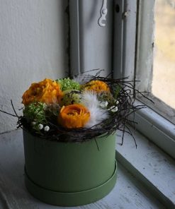 En påskeblomsteræske med orange blomster stående i en vindueskarm