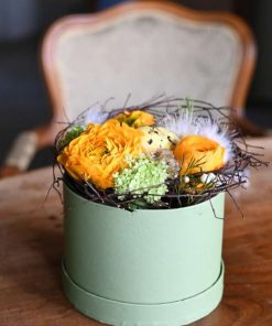Påske blomsteræske i orange toner med et plettet påskeæg i midten og fjer