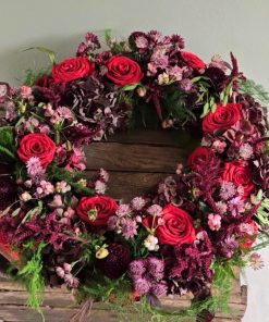 En blomsterkrans i røde og lilla farver