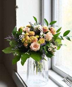 Buket i orange, ferskenfarvet og lilla farver i vindueskarm