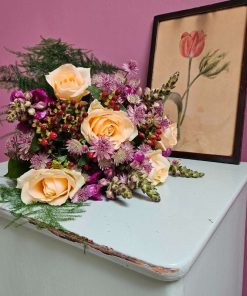 Buket i lys orange med bordeaux farver på grøn kommode