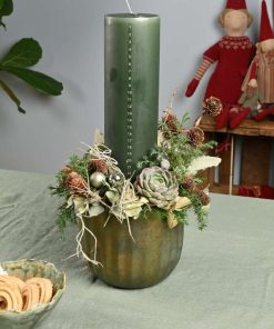 Kalenderlys juledekoration i grønne farver med naturpynt på bord med grøn dug