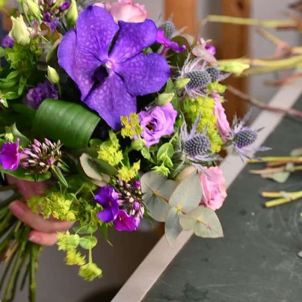 Buket i lilla farver med blandt andet vanda orkide, eustoma, manstro, phlox og eustoma