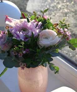 Buket af lilla blomster i et vindue