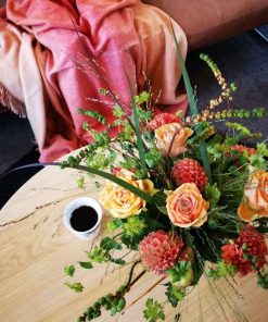 Buket i orange farver set oppefra på bord med kaffekop