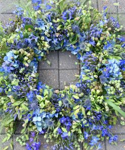 En begravelseskrans i blå farver med vilde græsser