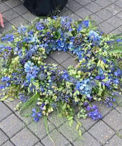 En begravelseskrans i blå farver med vilde græsser