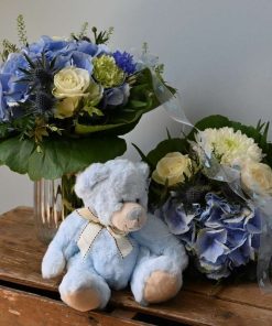 Mor og barn buket i blå farver med lyseblå bamse på brun trækasse