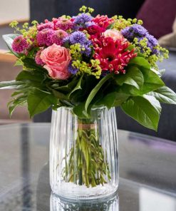 Buket i forskellige farver i glasvasepå et glasbord