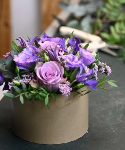 Blomsteræske med blomster i lilla farver på arbejdsbord