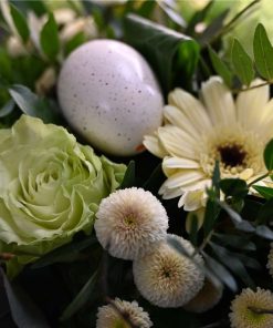 Nærbillede af et hvidt påskeæg i midten af en buket i sarte gule farver