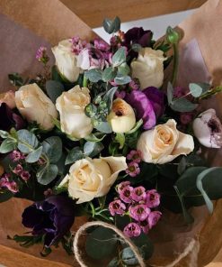 Buket med roser, ranunkler og franske anemoner i brunt papir