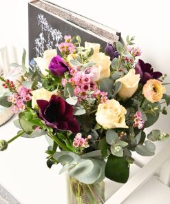 Buket med roser, ranunkler og franske anemoner på reol