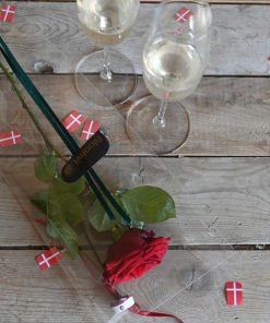 En rød studenterhue og en rød rose set oppefra med to glas champagne ved siden af