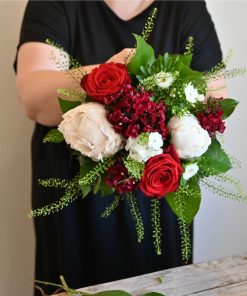 Buket i hvide og røde farver der holdes af en person