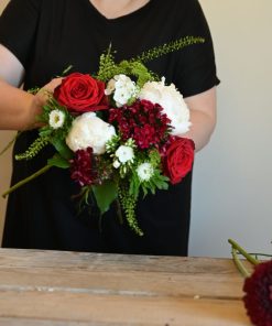 Buket i hvide og røde farver der holdes af en person