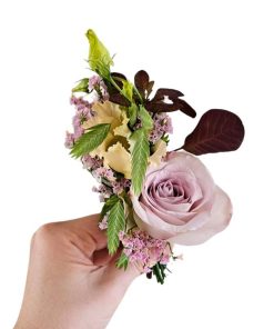 Knaphulsblomst holdes i hånd, med lilla rose og andre blomster