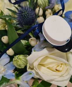 Nærbillede af en lille blå studenterhue og hvide og blå blomster