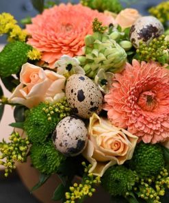 Nærbillede af Blomsteræske med forskellige blomster og små påskeæg