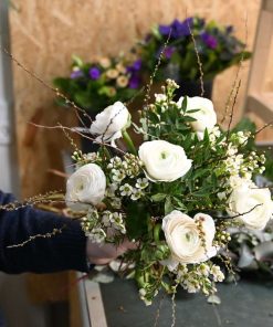 Buket med hvide ranunkler holdes i hånd