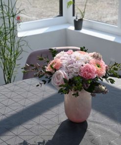 Buket i lyserøde farver på et bord med grå dug