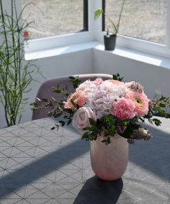 Buket i lyserøde farver på et bord med grå dug